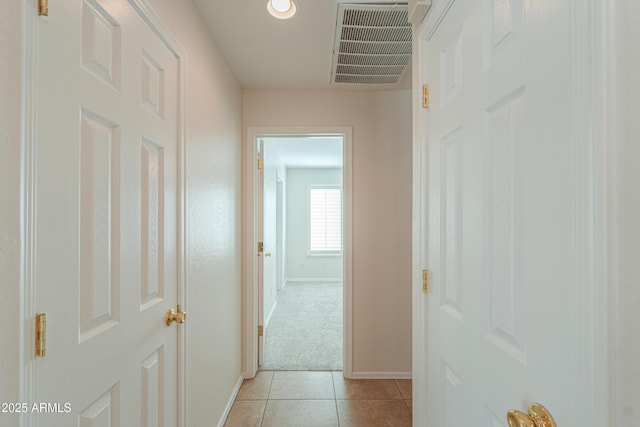 hall featuring light colored carpet, light tile patterned floors, baseboards, and visible vents