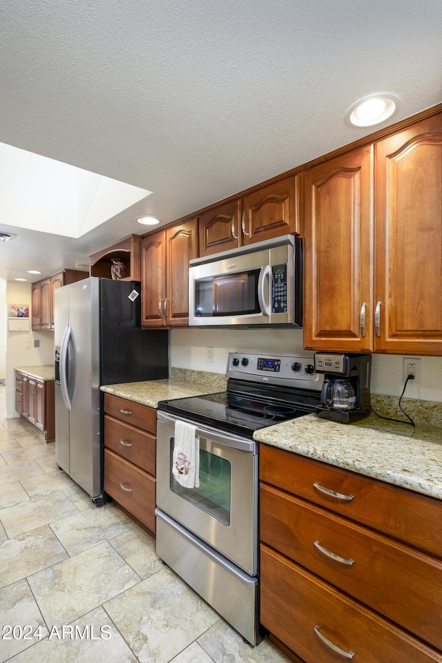 kitchen featuring a skylight, light stone counters, and stainless steel appliances