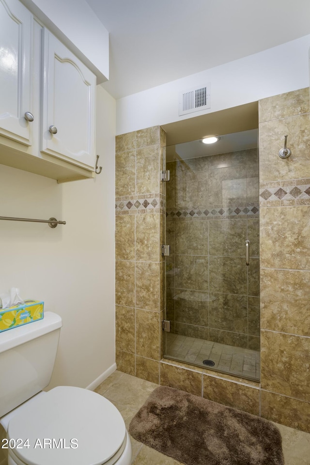 bathroom with tile patterned flooring, toilet, and a shower with shower door