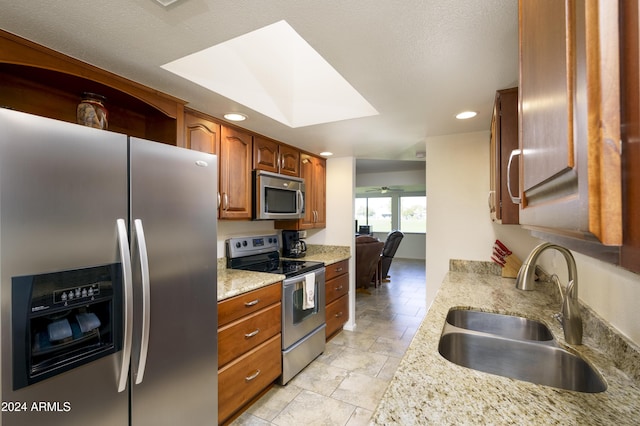 kitchen featuring light stone counters, sink, and stainless steel appliances