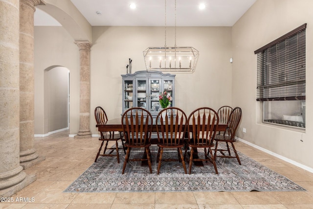 dining space with arched walkways, baseboards, and decorative columns