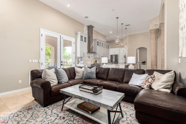 living area with light tile patterned flooring, baseboards, recessed lighting, french doors, and arched walkways