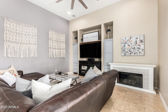 living area featuring baseboards, a ceiling fan, built in features, and a fireplace