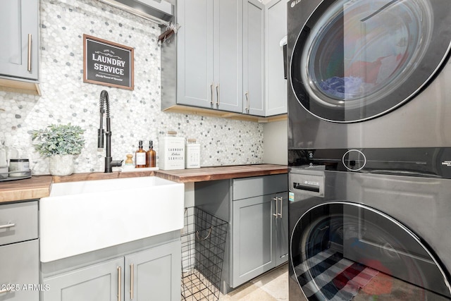 laundry room featuring a sink, stacked washer and dryer, and cabinet space