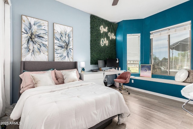 bedroom with built in study area, a ceiling fan, baseboards, and wood finished floors