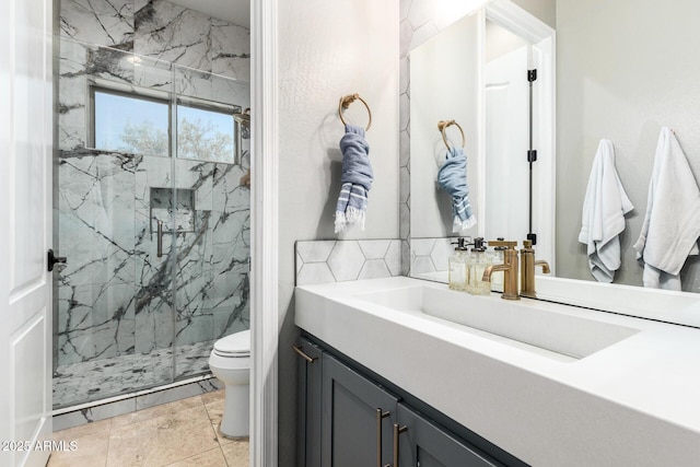bathroom featuring vanity, a marble finish shower, and toilet