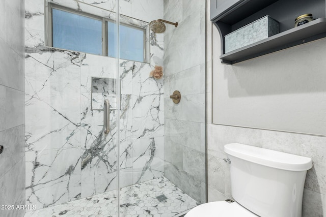 bathroom featuring toilet, tile walls, and a marble finish shower
