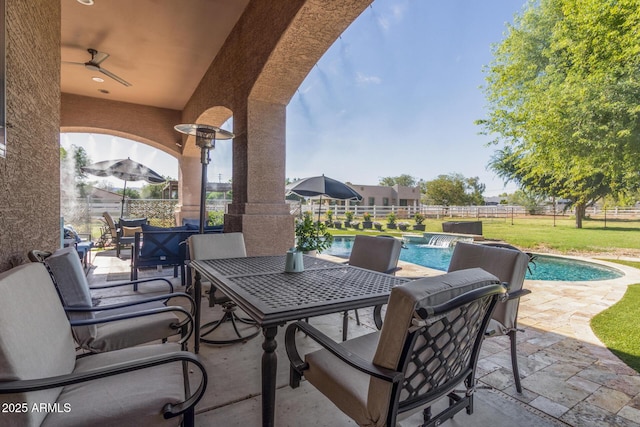 view of patio featuring fence, ceiling fan, a fenced in pool, and outdoor dining space