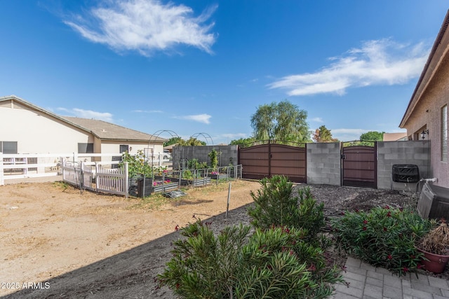 view of yard with fence, a garden, and a gate