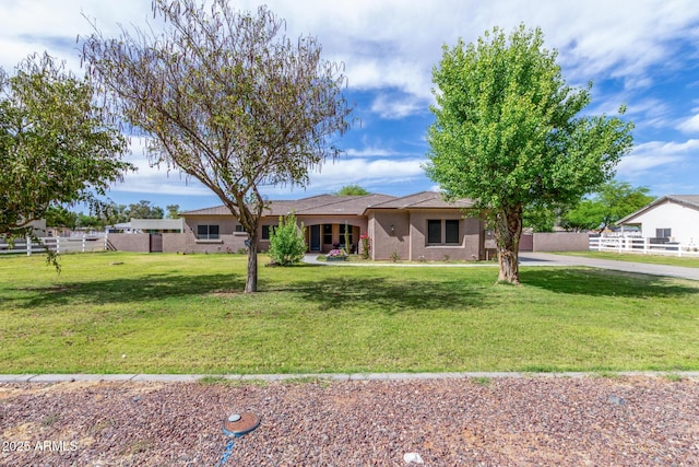 ranch-style home featuring fence and a front lawn