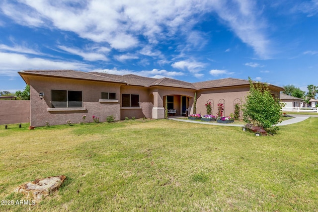 back of house with a lawn and stucco siding