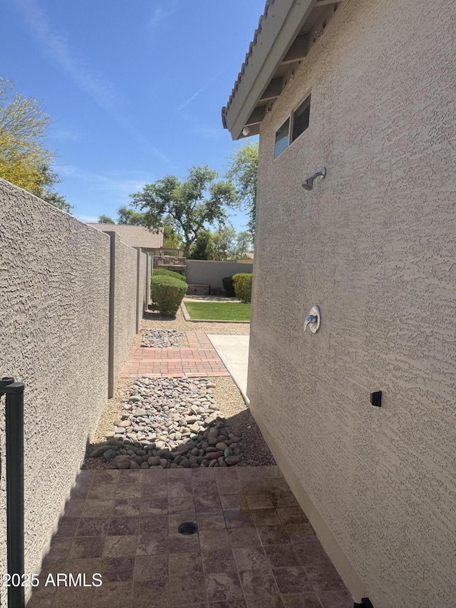 view of side of home featuring stucco siding, fence, and a patio