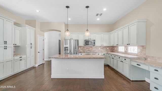 kitchen with visible vents, tasteful backsplash, light stone counters, arched walkways, and appliances with stainless steel finishes