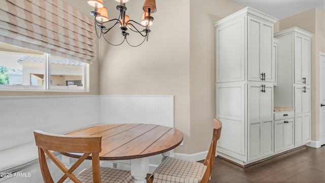 dining area with dark wood-type flooring, wainscoting, and a notable chandelier
