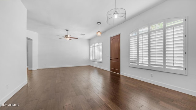unfurnished living room with dark wood-type flooring, a ceiling fan, and baseboards