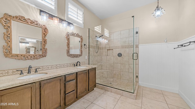 full bathroom featuring tile patterned floors, wainscoting, a sink, and a stall shower