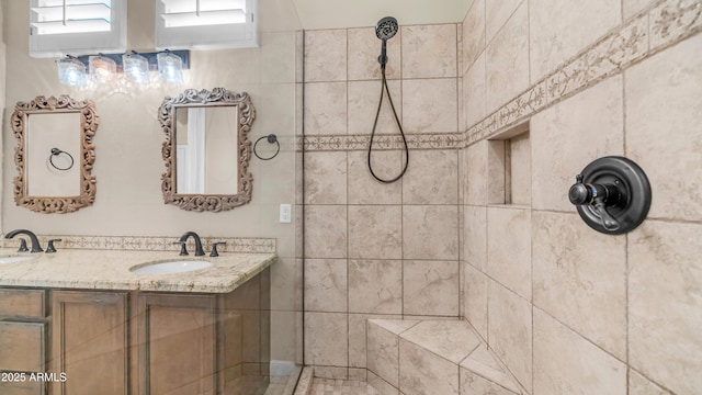 bathroom featuring double vanity, a sink, and tiled shower