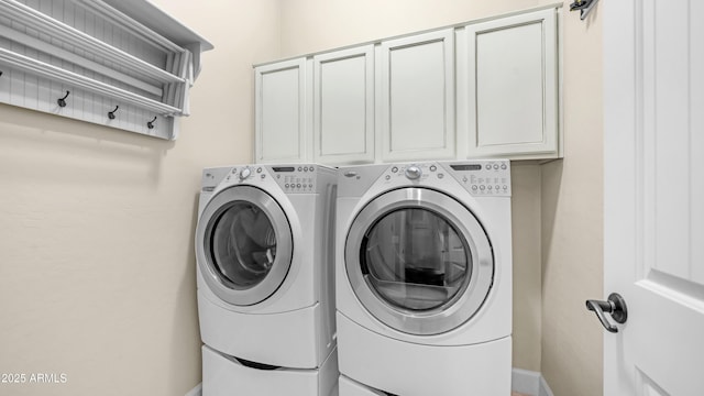 laundry room with baseboards, cabinet space, and washing machine and clothes dryer