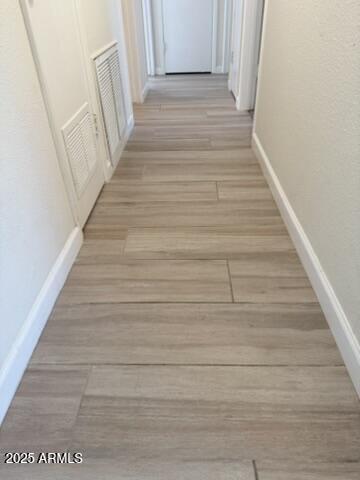 corridor featuring visible vents, light wood finished floors, and baseboards
