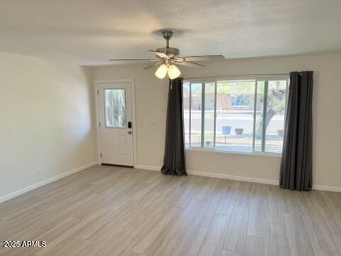 interior space with light wood-type flooring, baseboards, and ceiling fan
