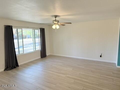 unfurnished room featuring ceiling fan, baseboards, and light wood-type flooring