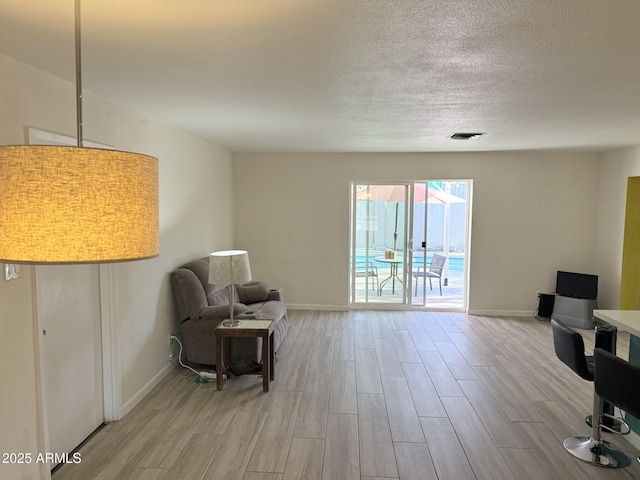 sitting room featuring light wood-type flooring, baseboards, and visible vents