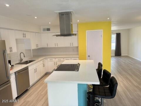 kitchen featuring a sink, visible vents, island range hood, a kitchen island, and appliances with stainless steel finishes