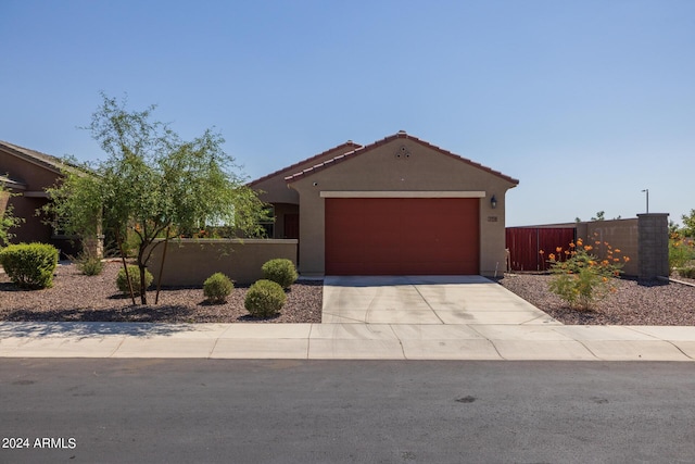 view of front of home featuring stucco siding, driveway, a garage, and fence