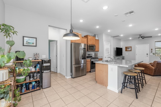 kitchen with an island with sink, hanging light fixtures, stainless steel appliances, sink, and ceiling fan