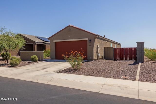 view of front of property featuring an attached garage, fence, a tile roof, stucco siding, and driveway