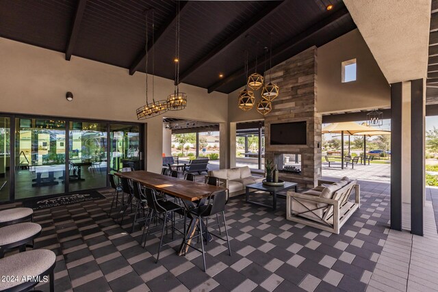 dining area featuring high vaulted ceiling, a fireplace, beamed ceiling, and plenty of natural light