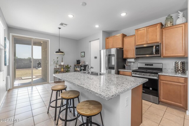 kitchen with pendant lighting, an island with sink, a kitchen bar, stainless steel appliances, and sink