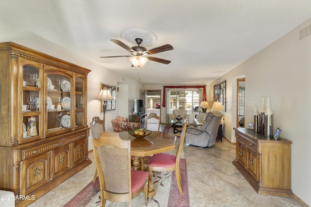 dining area with a textured ceiling and ceiling fan