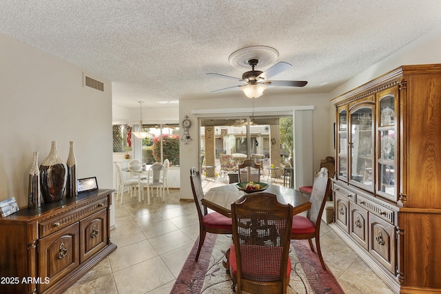 tiled dining space featuring a wealth of natural light, a textured ceiling, and ceiling fan