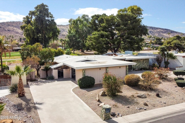 view of front facade with concrete driveway, a carport, and a mountain view