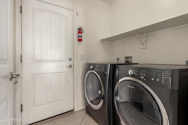 clothes washing area with light tile patterned floors and washer and clothes dryer