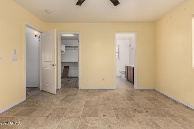 unfurnished bedroom with a spacious closet, a closet, ceiling fan, and ensuite bathroom