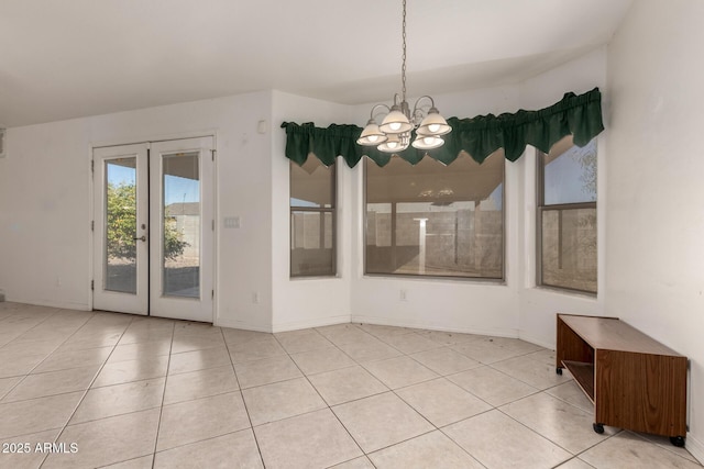 unfurnished dining area with light tile patterned flooring, a chandelier, and french doors