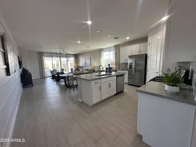 kitchen with a wealth of natural light, appliances with stainless steel finishes, white cabinets, and a sink