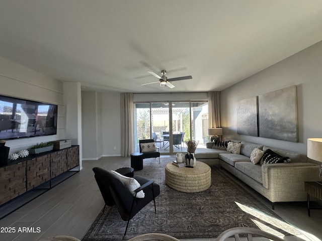 living room featuring wood finished floors, a ceiling fan, and baseboards