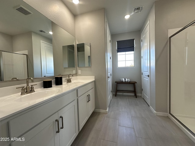 bathroom with visible vents, a sink, and a shower stall