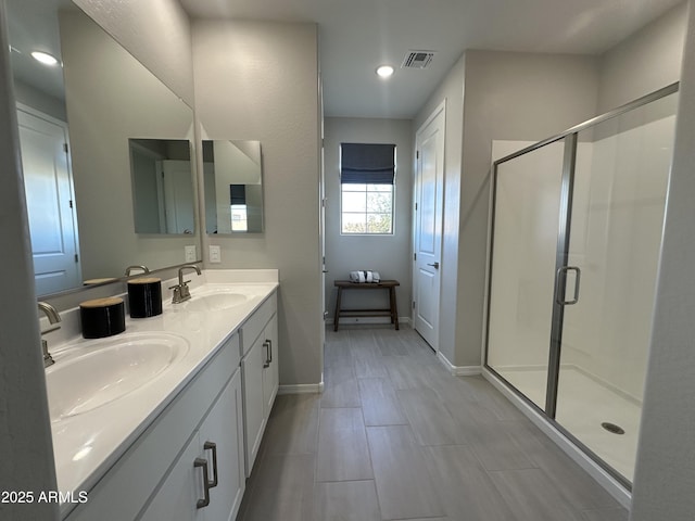 full bath with double vanity, a stall shower, a sink, and visible vents