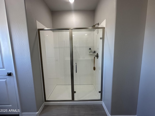 bathroom with a shower stall, baseboards, and tile patterned floors