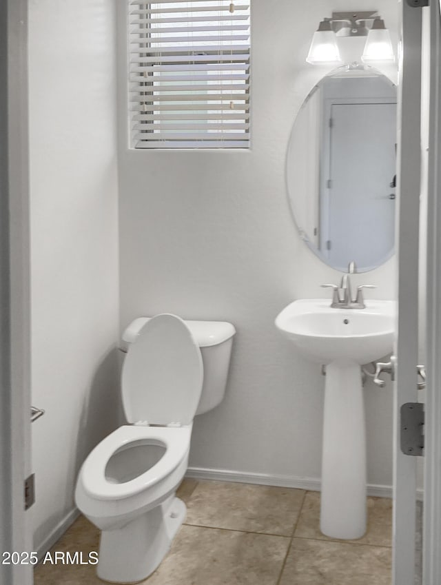 bathroom with toilet, sink, and tile patterned floors