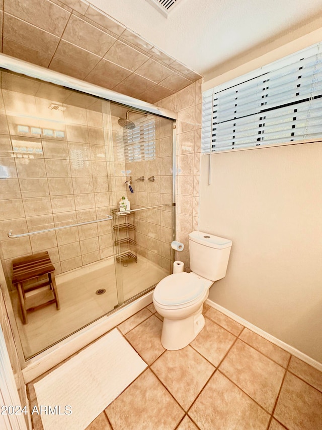 bathroom featuring walk in shower, tile patterned flooring, and toilet