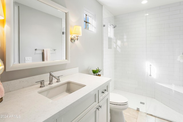 bathroom with vanity, toilet, tiled shower, and tile patterned floors