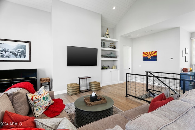 living room featuring light hardwood / wood-style floors, high vaulted ceiling, wood ceiling, and built in shelves