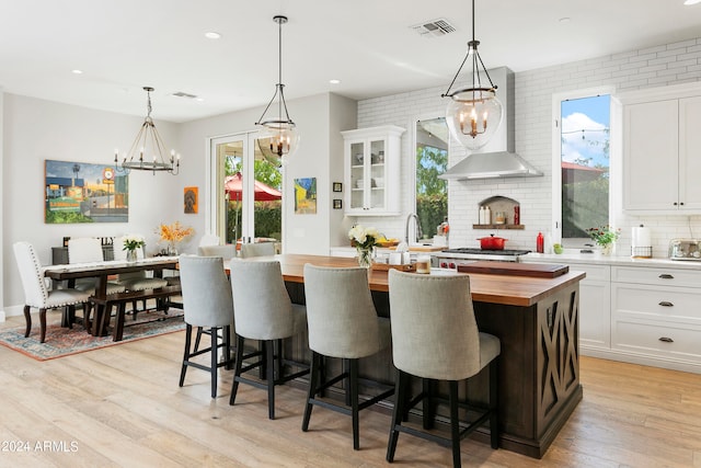 kitchen featuring wooden counters, a center island, white cabinets, and light hardwood / wood-style floors