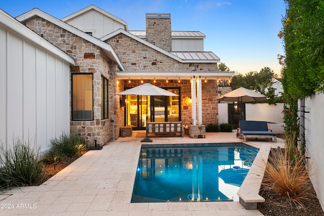 back house at dusk featuring a patio