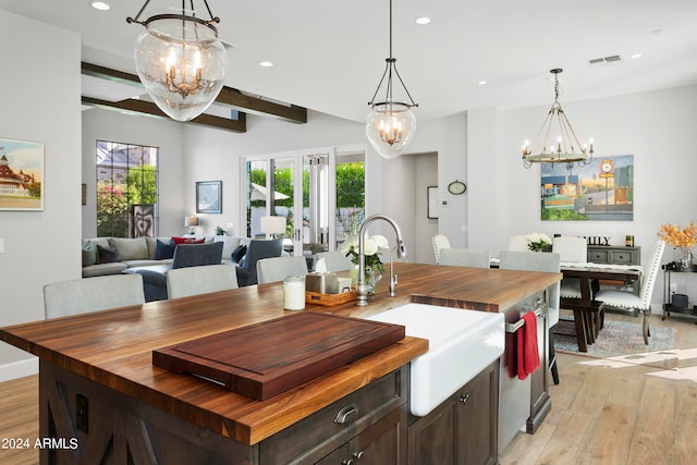 kitchen featuring a center island with sink, beamed ceiling, sink, and light hardwood / wood-style flooring